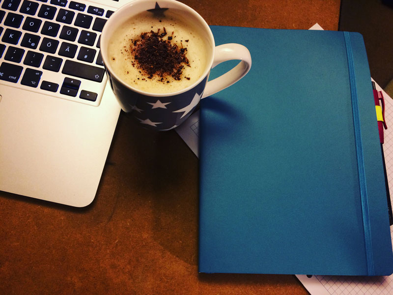 Notebook, ein Notizheft und ein Milchkaffee